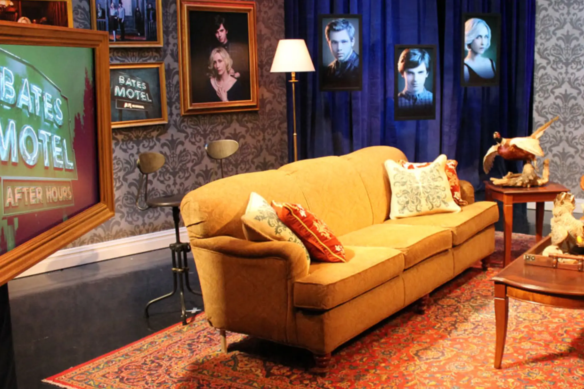Cozy set from _Bates Motel_ featuring a mustard-colored couch, decorative pillows, a wooden coffee table, and vintage decor on the walls